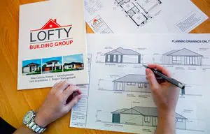 lofty building group custom home design plans on desk