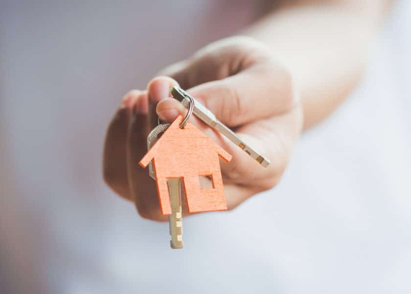 female hand holding house key real estate